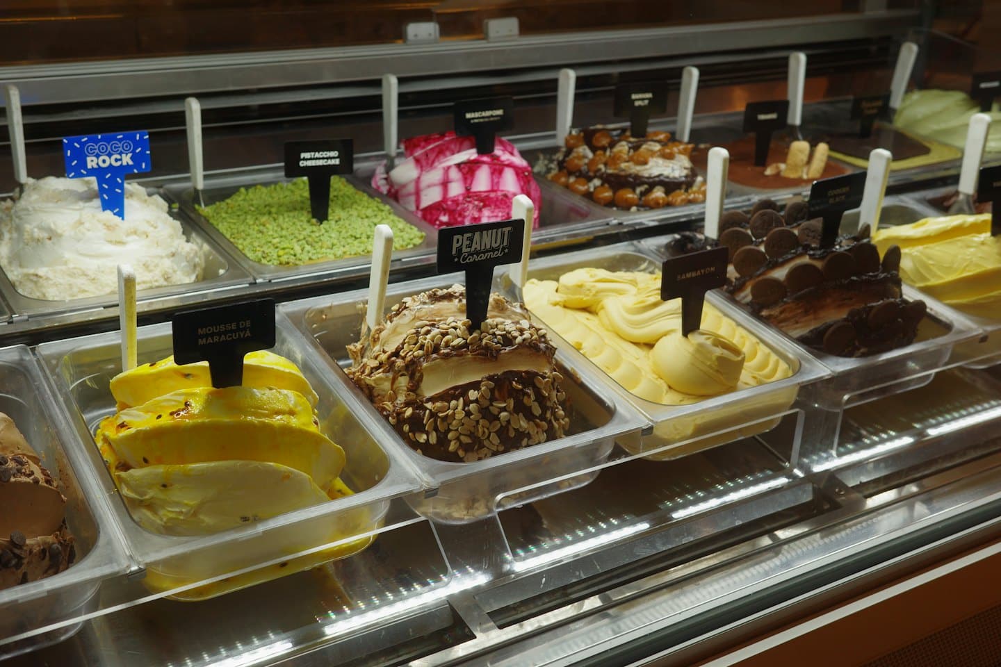Vetrina di vetro piena di file di gelati artigianali colorati.