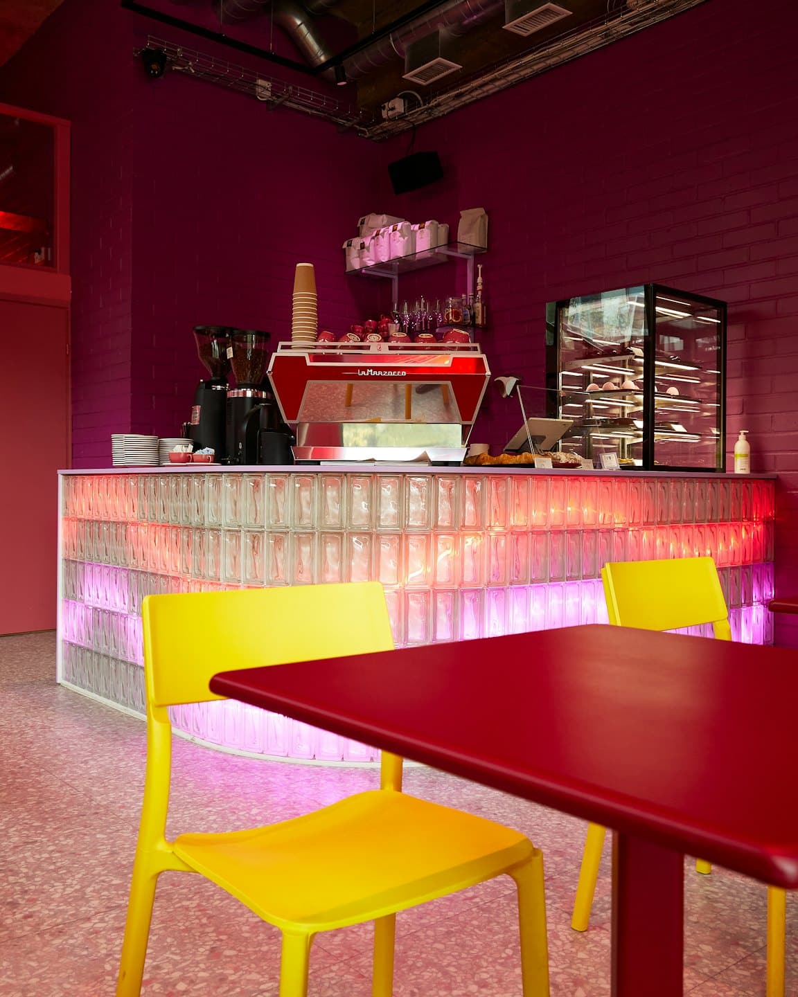 Interno di un moderno caffè con macchina per espresso rossa e tavoli.
