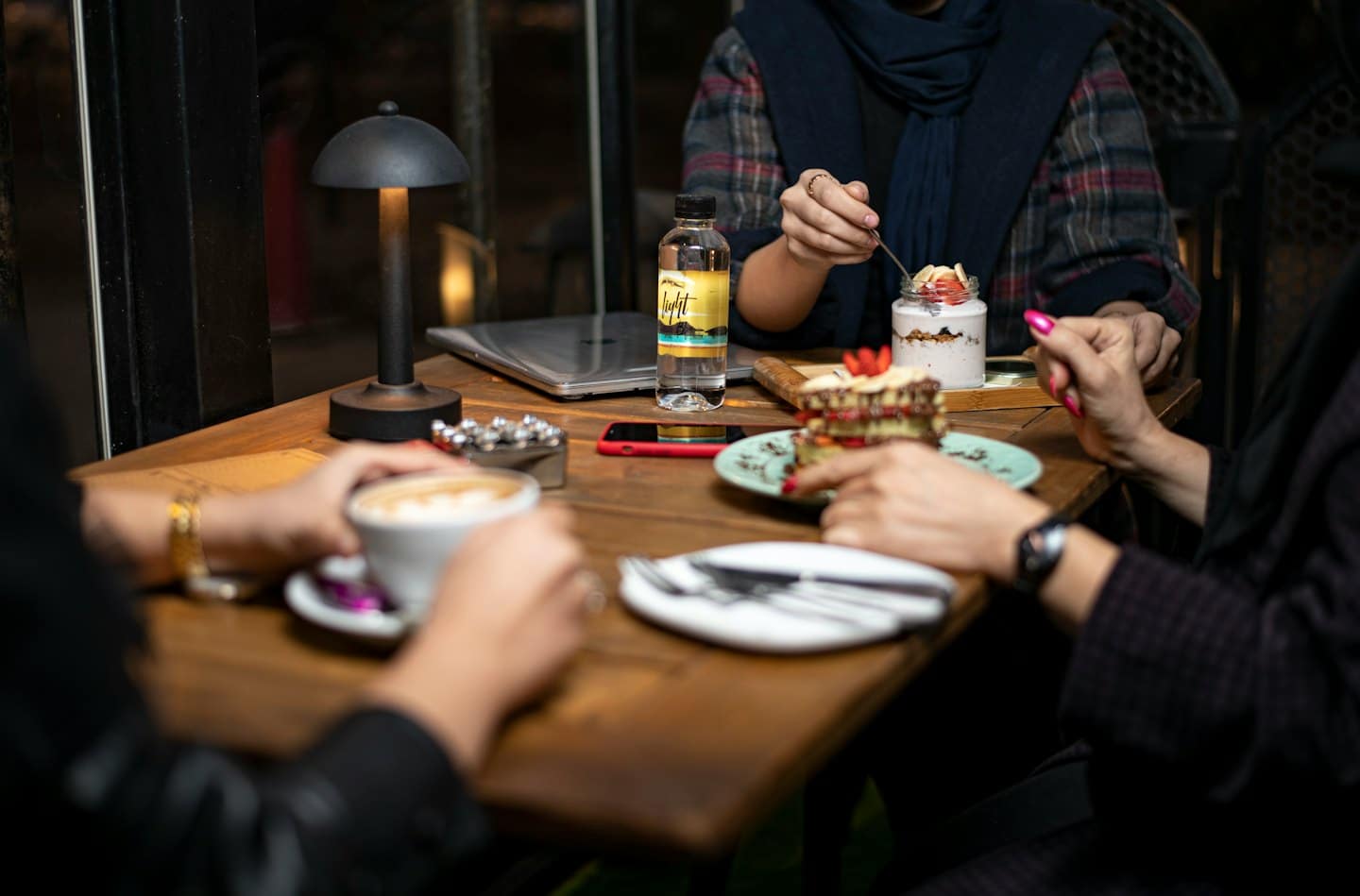 Persone che mangiano dolci e bevono caffè a un tavolino di un bar.