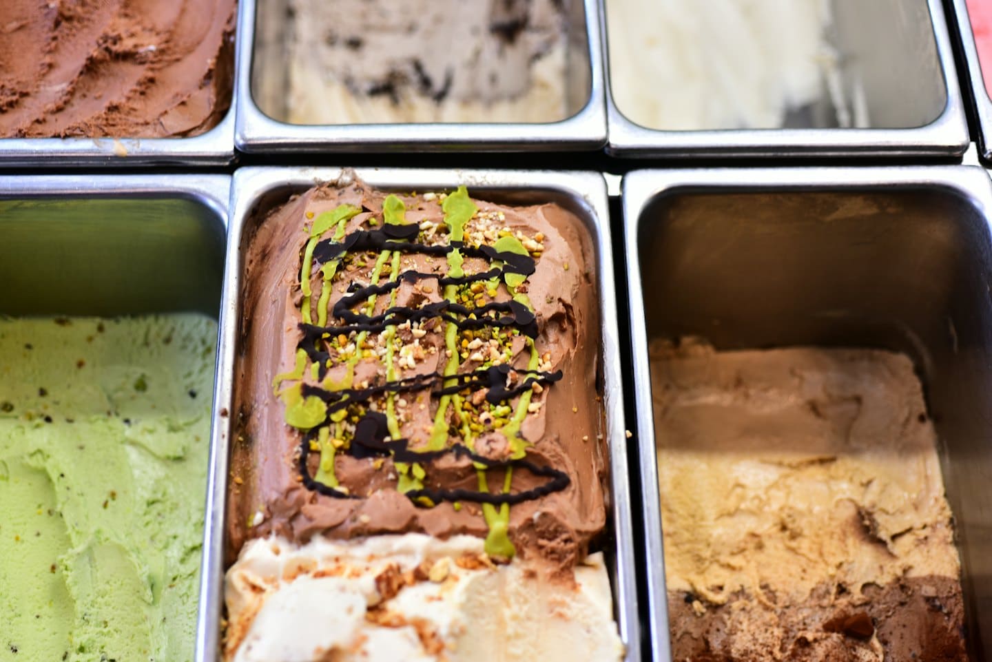 Vaschette di metallo piene di vari gusti colorati di gelato.