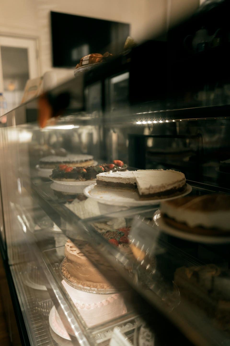 Varietà di torte e pasticcini disposti all'interno di una vetrina.