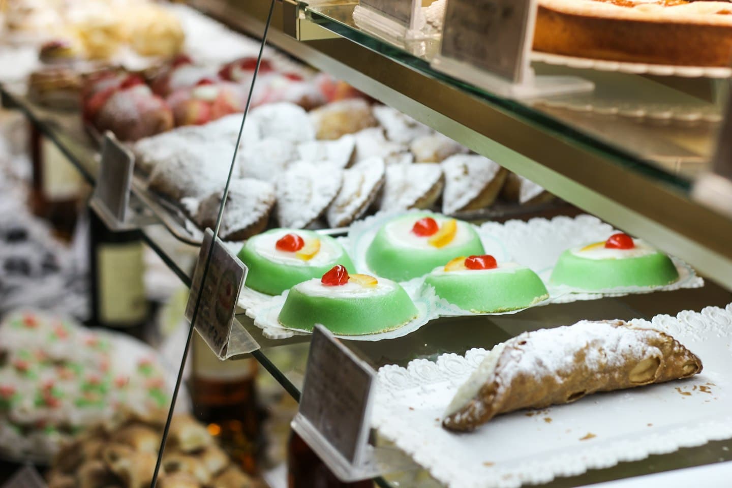 Pasticcini e torte su centrini di pizzo all'interno di una vetrina.